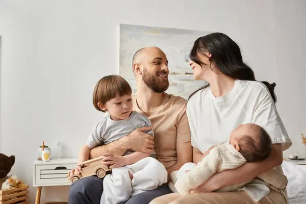 Good looking parents holding their little son and newborn baby and smiling lovingly at each other — Stock Photo