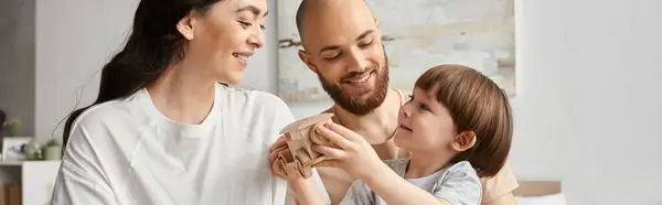 Padres modernos felices sonriendo alegremente mientras juegan con su pequeño hijo, concepto de familia, bandera - foto de stock