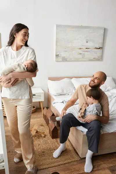 Вертикальный снимок современных родителей, счастливо улыбающихся друг другу, проводя время с детьми — стоковое фото