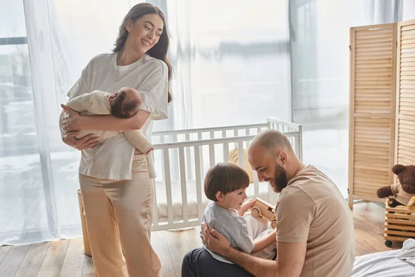 Beautiful mother holding her baby boy and looking lovingly at her husband and son, family concept — Stock Photo