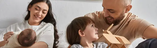 Cheerful young mother holding newborn baby next to bearded father hugging their little son, banner — Stock Photo