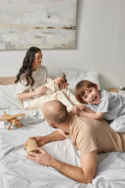 Vertical shot of modern beautiful family having great time relaxing and playing together in bedroom — Stock Photo