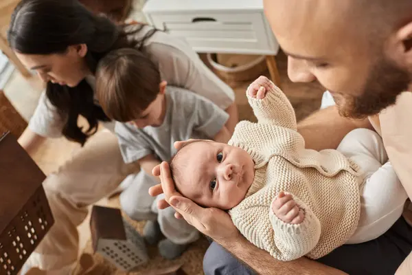 Focus on bearded father holding his newborn baby boy next to his blurred wife with their little son — Stock Photo