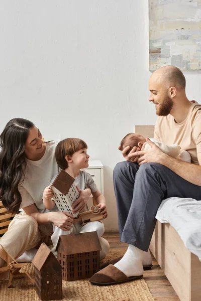 Happy modern parents in cozy homewear spending time with their little son and newborn baby, family — Stock Photo