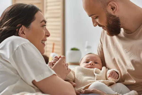 Happy young mother smiling at her bearded husband holding their newborn baby boy, family concept — Stock Photo