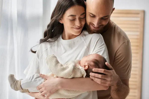Hermosos padres felices abrazando y sosteniendo a su bebé recién nacido amorosamente, concepto de familia - foto de stock