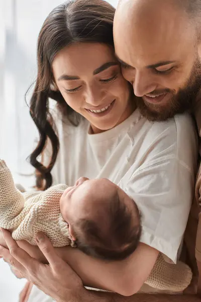 Vertical shot of loving modern parents hugging and smiling at their newborn baby boy, family — Stock Photo