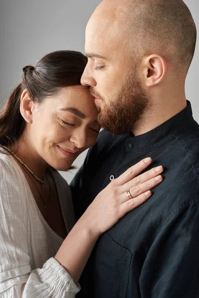 Plan vertical de joyeux beau couple serrant chaudement dans des tenues élégantes sur fond gris — Photo de stock