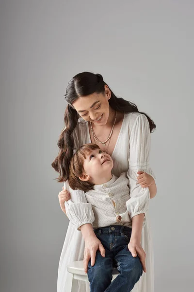 Vertikale Aufnahme freudige Mutter und ihr Vorschulkind lächeln einander an, Familienkonzept — Stockfoto