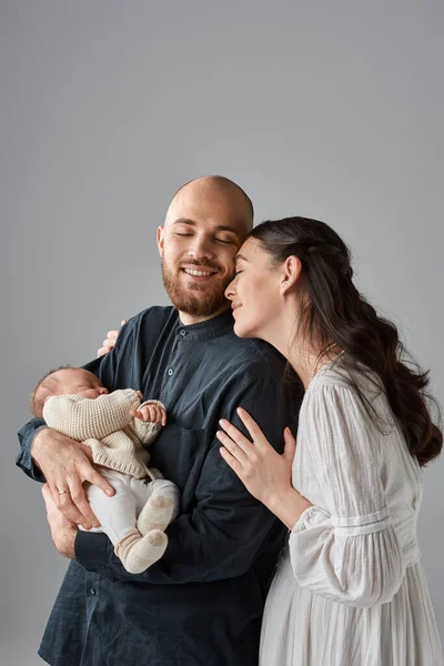 Vertical shot of beautiful parents in classy outfits hugging and holding their newborn baby, family — Stock Photo