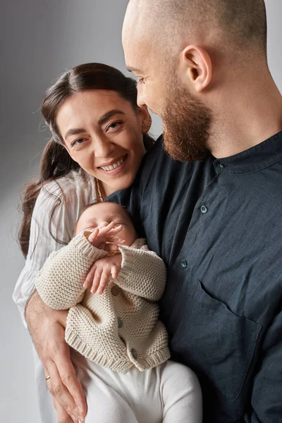 Tiro vertical de pai barbudo segurando seu menino enquanto sua esposa feliz olhando para a câmera, família — Fotografia de Stock