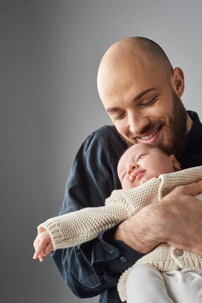 Vertical shot of happy bearded father holding his newborn baby boy and smiling joyfully, family — Stock Photo