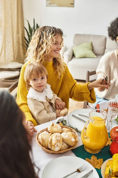 Happy mother sitting with daughter and holding hands while praying at Thanksgiving table, gathering — Stock Photo