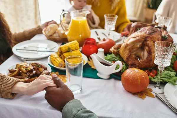 Cortado multirracial homem e mulher de mãos dadas e orando no Dia de Ação de Graças ao lado do jantar festivo — Fotografia de Stock