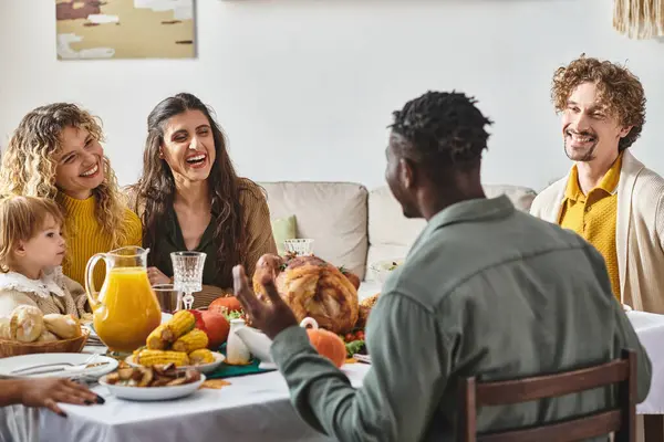 Happy multiethnic friends talking near toddler girl during Thanksgiving celebration, festive day — Stock Photo