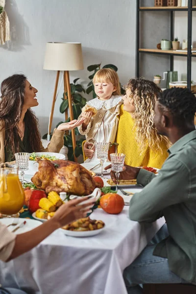 Thanksgiving tradition, happy interracial relatives looking at toddler girl near festive table — Stock Photo