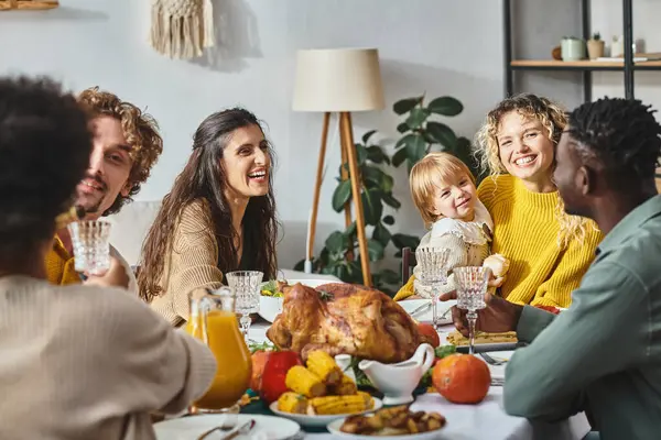 Feliz interracial familia y amigos teniendo vacaciones cena juntos en Acción de Gracias, pavo asado - foto de stock