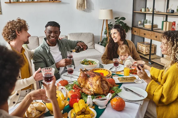 Familia multicultural disfrutando de la cena de Acción de Gracias en la mesa festiva, madre e hijo cerca del pavo - foto de stock