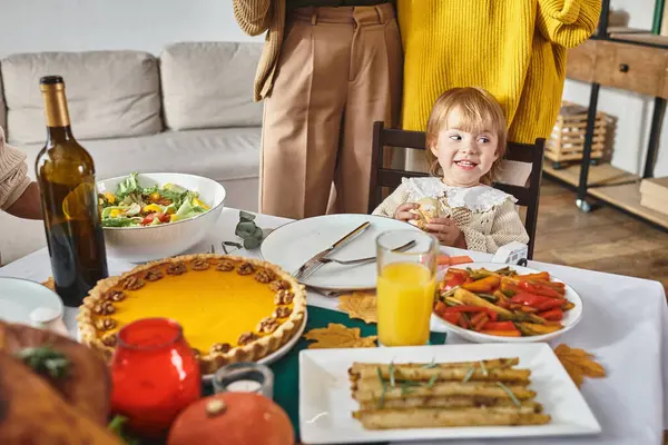 Adorable jeune fille regardant loin et souriant près de tarte à la citrouille pendant la célébration de Thanksgiving — Photo de stock