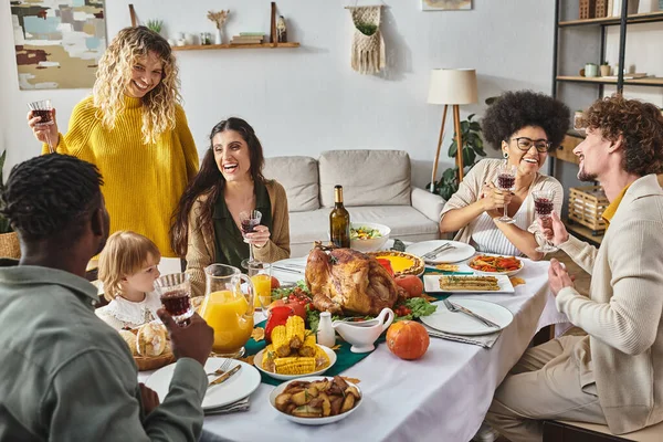 Amigos multiétnicos y la familia celebrando Acción de Gracias con la niña pequeña, tiempo de calidad - foto de stock