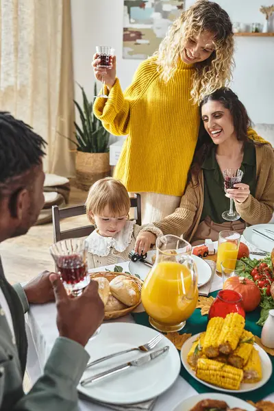 Joyeux couple lgbt célébrer Thanksgiving avec tout-petit bébé fille, acclamer et rire à la maison — Photo de stock