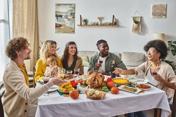 Happy man passing plate with roasted potatoes to african american woman during Thanksgiving dinner — Stock Photo