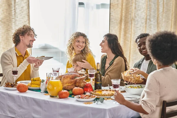 Família multirracial feliz e amigos desfrutando de refeições e bebidas enquanto se reúnem no dia de Ação de Graças — Fotografia de Stock