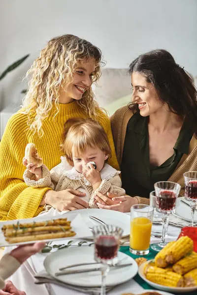 Alegre casal lésbico e bebê da criança desfrutando delicioso jantar enquanto se reúne no Dia de Ação de Graças — Fotografia de Stock