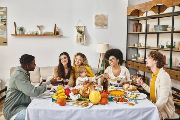 Alegres amigos multiétnicos y familiares compartiendo sabrosa cena mientras celebran Acción de Gracias juntos - foto de stock