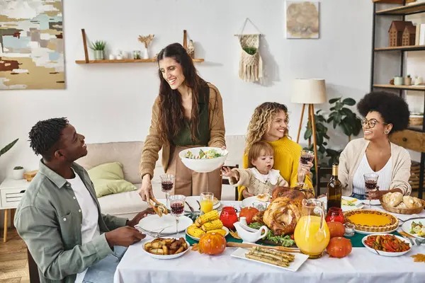 Happy woman serving salad to african american man near friends and family on Thanksgiving day — Stock Photo