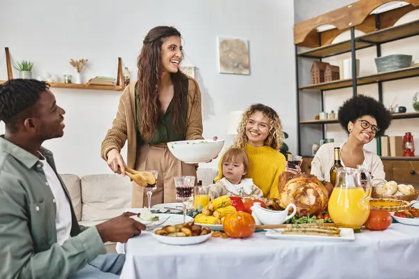 Happy woman serving salad near multicultural friends and family during Thanksgiving celebration — Stock Photo