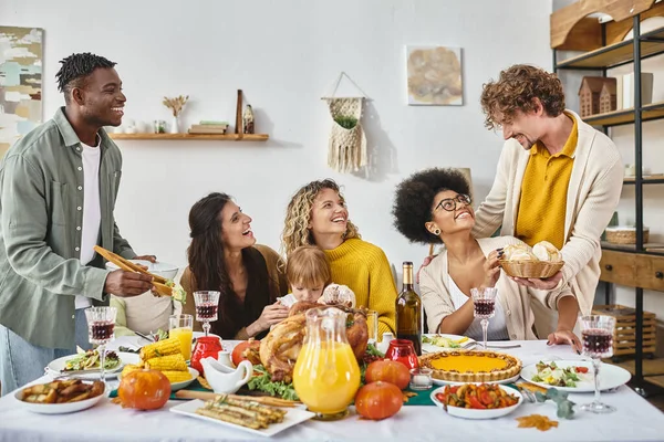 Tradiciones de acción de gracias y alegría, amigos multiétnicos y reunión familiar en la mesa con el pavo - foto de stock