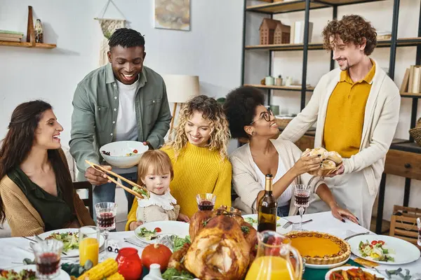 Celebración de Acción de Gracias, felices amigos multiétnicos y reunión familiar a la mesa con pavo - foto de stock
