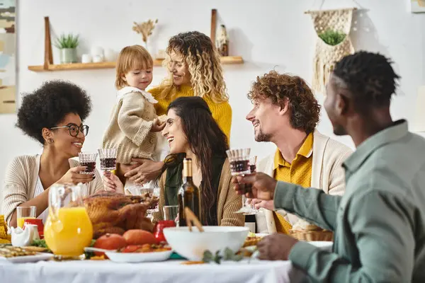 Feliz Ação de Graças, mulheres multiétnicas alegres copos de vinho perto de amigos e familiares — Fotografia de Stock