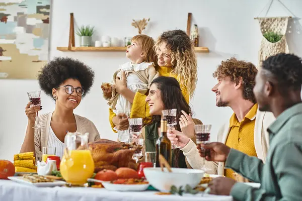 Feliz Ação de Graças, amigos multiétnicos positivos e família torcendo com copos de vinho tinto — Fotografia de Stock