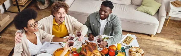 Happy Thanksgiving, joyful interracial friends and family clinking glasses of wine, top view banner — Stock Photo