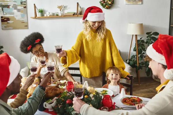 Merry Christmas celebration, happy multicultural friends and family cheering glasses near toddler — Stock Photo