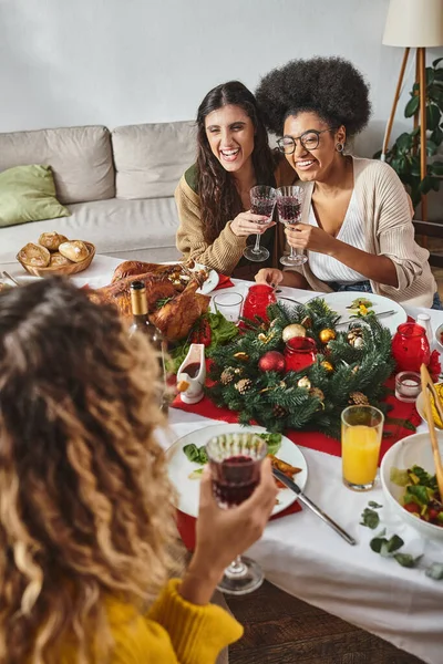 Familiares alegres en atuendo casual hablando con parientes sentados en la mesa festiva, Navidad - foto de stock