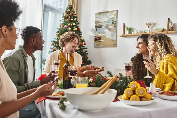 Gran familia multicultural pasar un buen rato celebrando la Navidad y disfrutando de un almuerzo festivo - foto de stock