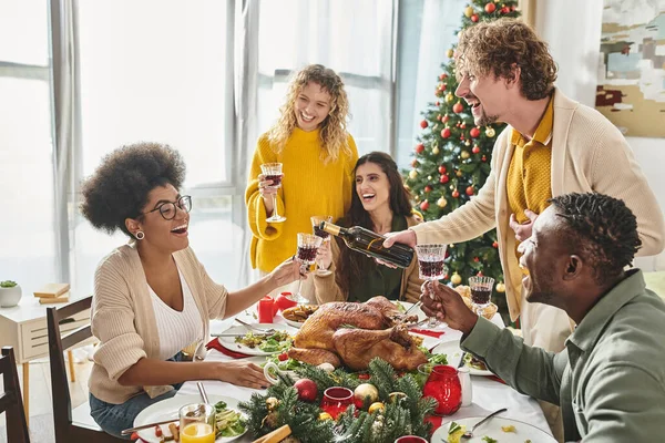 Fröhliche multiethnische Verwandte, die viel Spaß miteinander haben, lachen und Wein trinken, Weihnachten — Stockfoto