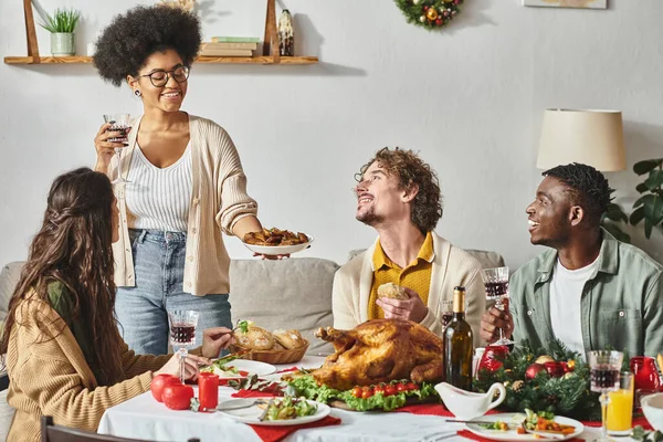 Alegres parientes multiculturales mirándose y sonriéndose mientras disfrutan de la fiesta de Navidad - foto de stock