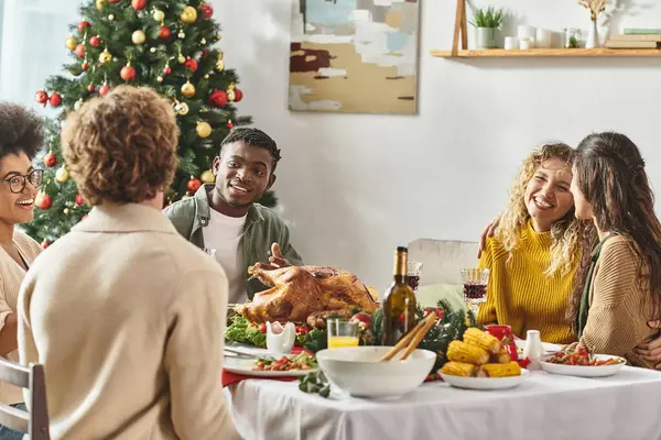 Jeune famille multiraciale célébrant Noël ensemble à la table de vacances avec dinde et vin — Photo de stock