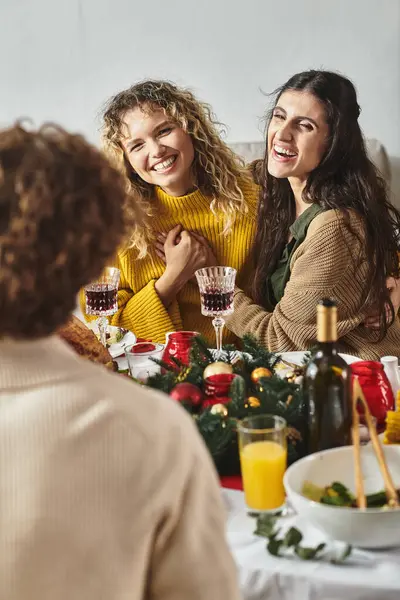 Loving lgbt couple sitting at festive table and laughing sincerely holding hands, Christmas — Stock Photo