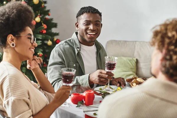 Young african american couple sitting at festive table enjoying holiday lunch with family, Christmas — Stock Photo