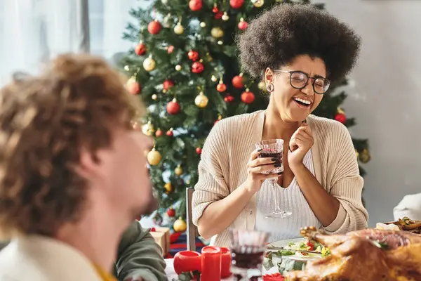 Afro-americana rindo sinceramente cercada por seus parentes na mesa festiva, Natal — Fotografia de Stock