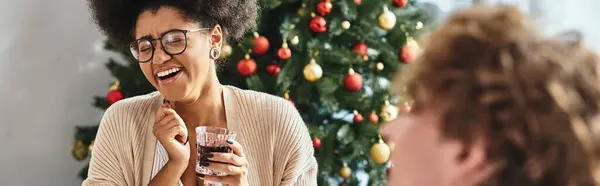 Giovane donna americana allegra africana che tiene il bicchiere di vino e ride sinceramente, Natale, striscione — Foto stock