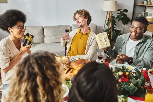 Feliz familia multiétnica grande pasar un buen rato juntos en el almuerzo de vacaciones y beber vino, Navidad - foto de stock