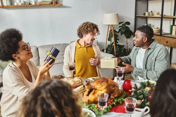 Cheerful multiracial family members talking and smiling at each other and holding gifts, Christmas — Stock Photo