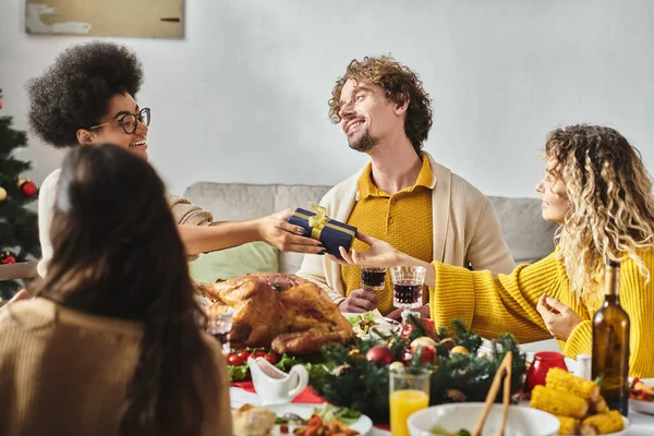 Jovens parentes multirraciais desfrutando de conversa e vinho sorrindo um para o outro, Natal — Fotografia de Stock