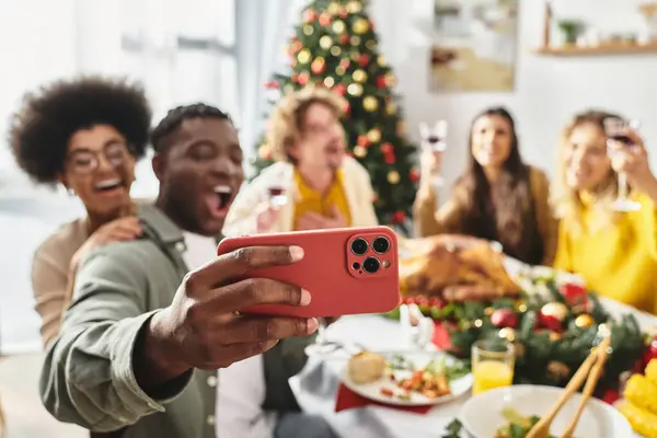 Happy multiethnic family members taking selfie at festive table with wine and food, blurred backdrop — Stock Photo